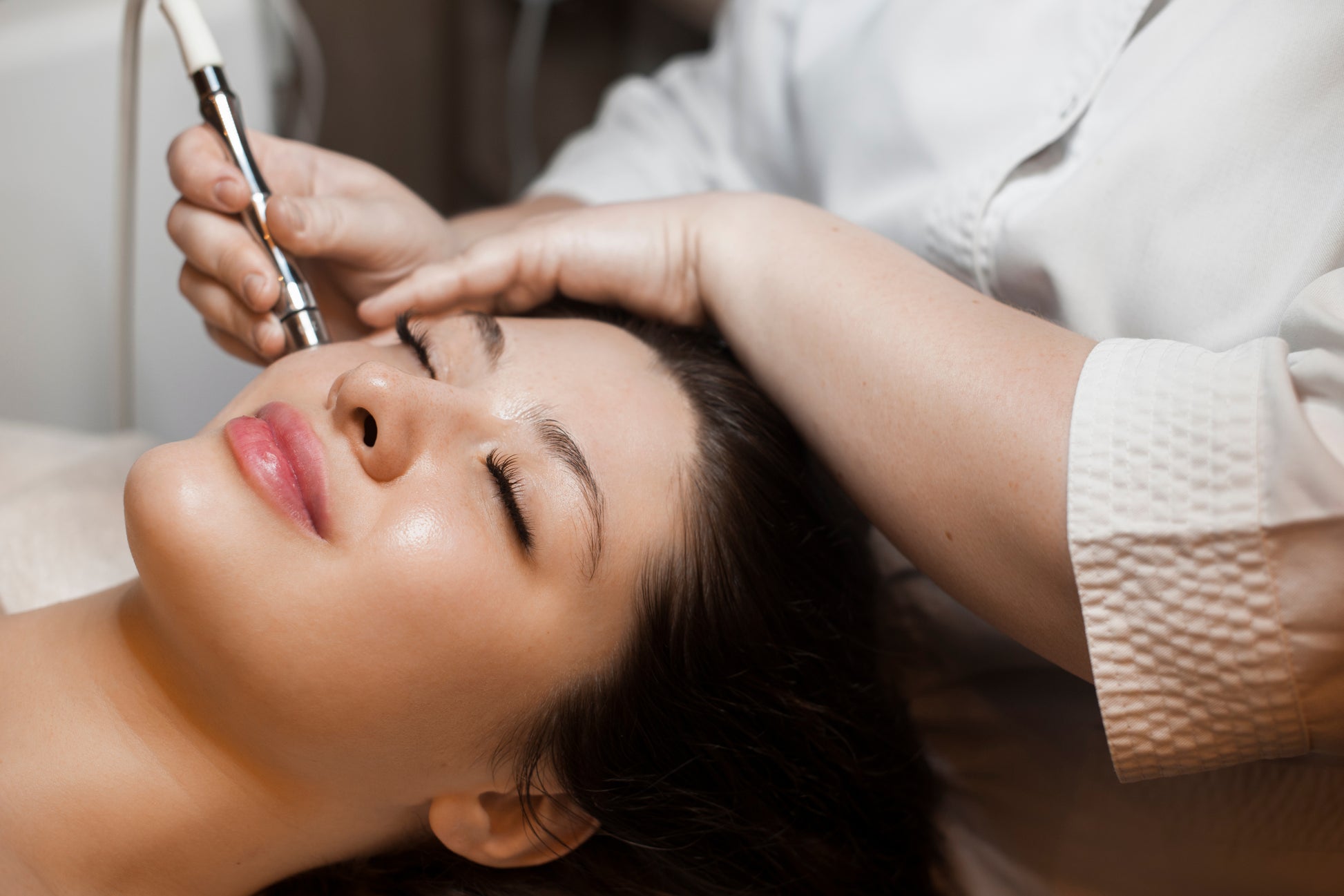 Doctor doing microneedling treatment on a girl's face