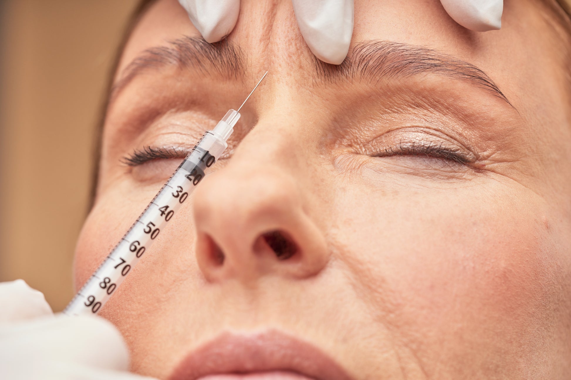 Close-up of a person receiving a facial injection with a syringe.