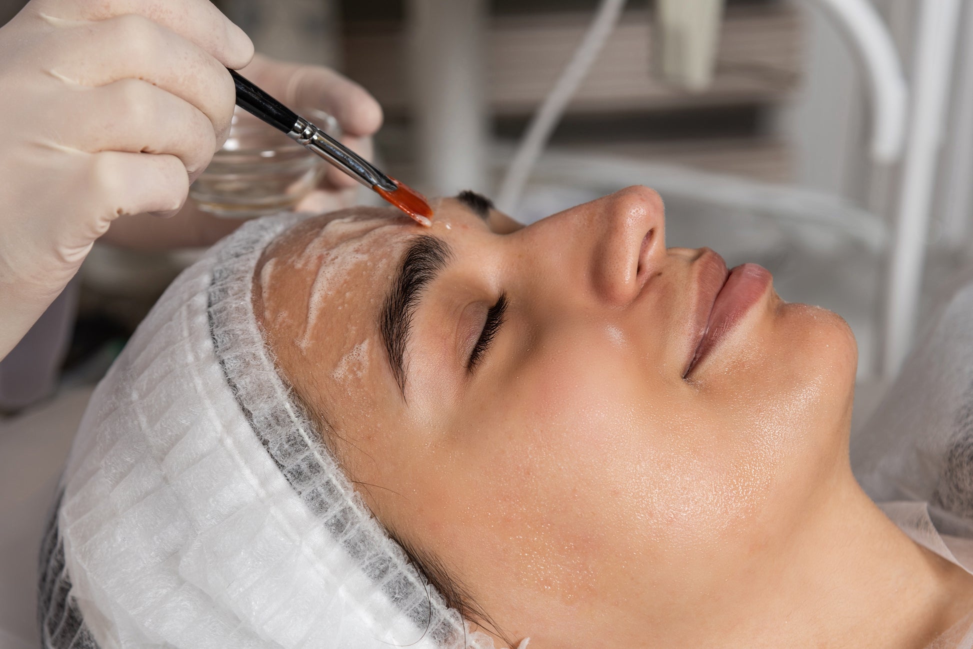 Person receiving a facial treatment with a brush applying a substance to their face.