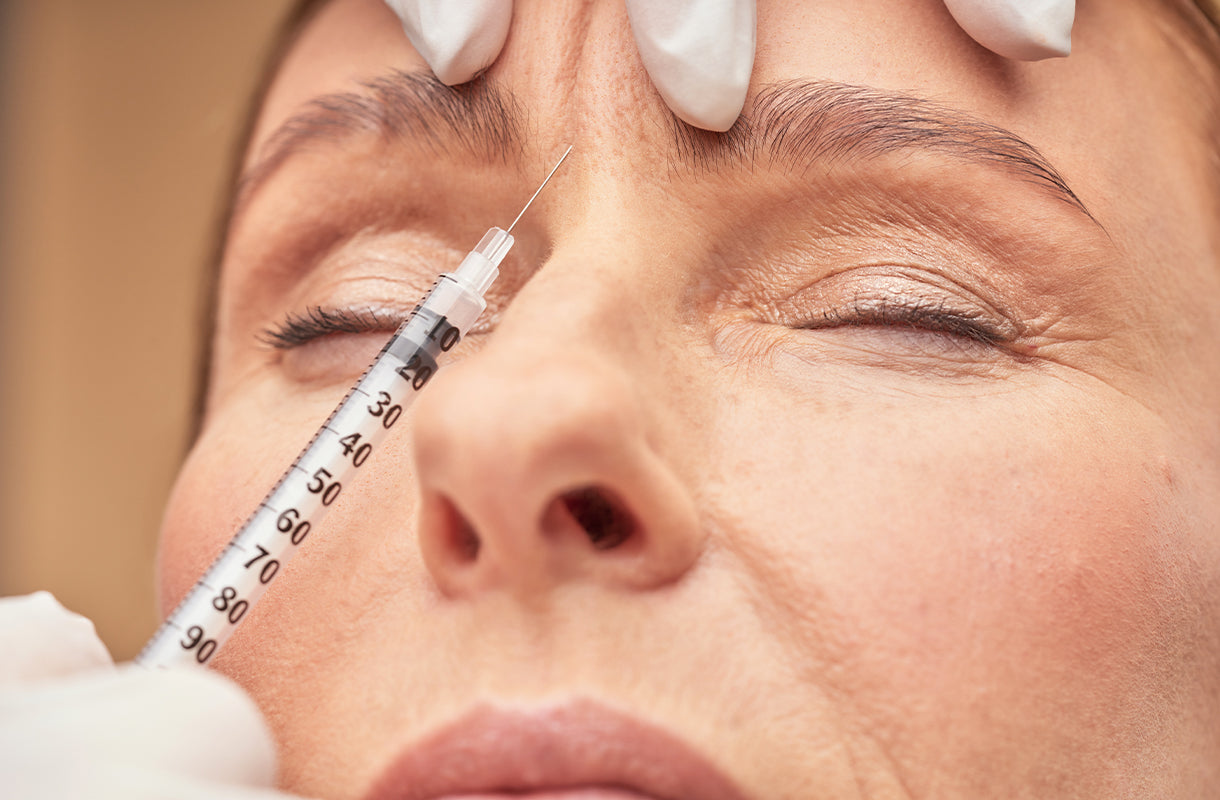 Close-up of a person receiving a facial injection with a syringe.
