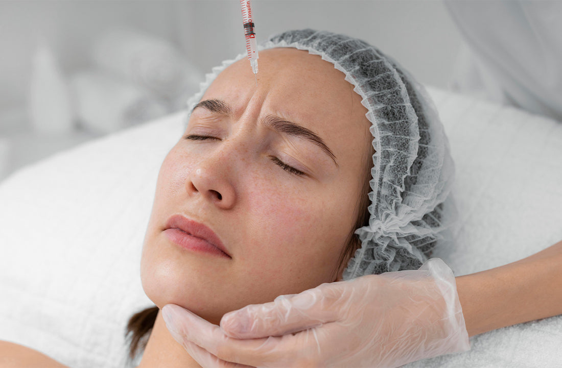 Woman receiving a facial treatment with a needle gun, wearing a hairnet and gloves.