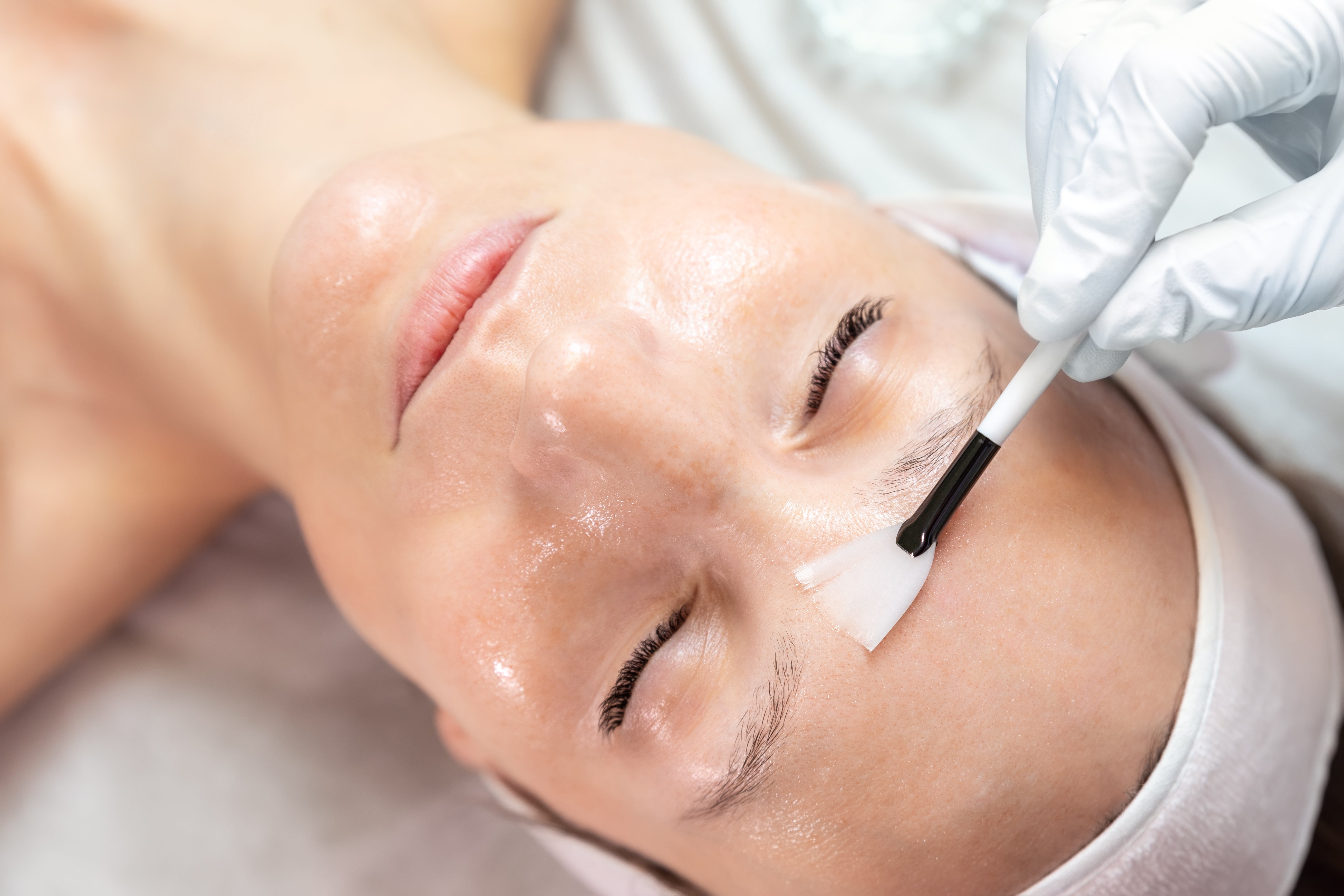 Person receiving a lux block treatment with a brush applying product to the face.