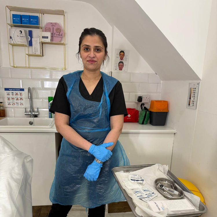 MedLaser Clinics Staff wearing a blue apron and gloves, standing in a clinical setting with medical equipment.